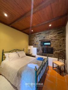a bedroom with a bed and a stone wall at Casa do Passadiço in Espiunca