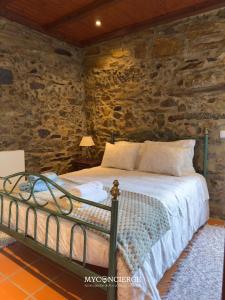 a bedroom with a bed in a stone wall at Casa do Passadiço in Espiunca