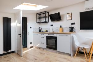 a kitchen with white cabinets and a tv on the wall at Apartament Green in Rzeszów