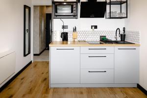 a kitchen with white cabinets and a wooden floor at Apartament LOFT in Rzeszów