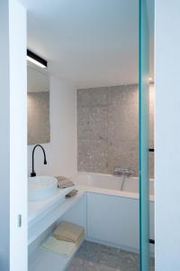 ein weißes Badezimmer mit einer Badewanne und einem Waschbecken in der Unterkunft Hotel Princess in Ostende