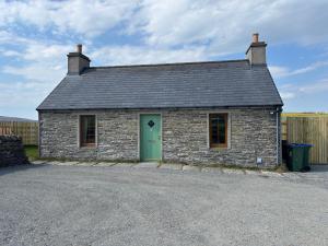 a small brick building with a green door at Peedie Orkney Cottage in Orkney