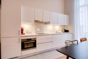 a white kitchen with white cabinets and a table at The Ghentian Suites by Domani Hotels in Ghent