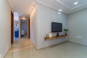 Una sala de estar con un televisor en una pared blanca. en Thom's House, en Santa Teresa