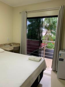 a bedroom with a bed and a large window at HOTEL LISBOA in Capanema