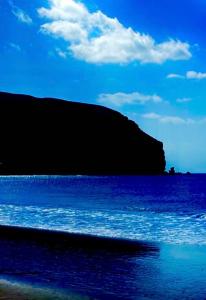 a beach with blue water and a hill in the background at Berlin Lovely in Gran Tarajal