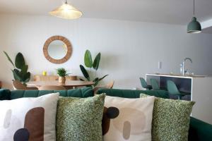 a living room with a green couch with pillows at Torreira Beachside House in Torreira +24 photos