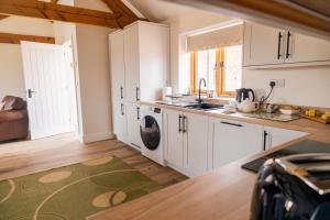 a kitchen with white cabinets and a washing machine at Oak at Pinfold Barns in Loppington