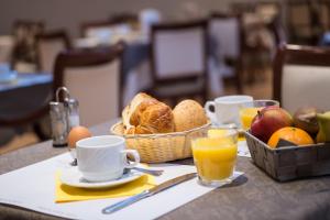 Ein Tisch mit einem Brotkorb und Bechern mit Orangensaft in der Unterkunft Hotel Princess in Ostende