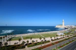 a view of the beach and the ocean with a lighthouse at Studio de charme face corniche de Casablanca in Casablanca