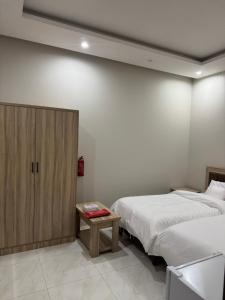 a bedroom with two beds and a wooden cabinet at غرفة وحمام مفروشة in Riyadh