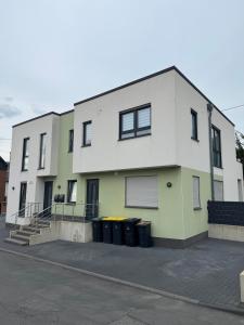 a white and green house with trash cans in front of it at Zentral & Ruhig - Apartment für 6 Gäste in Top Lage! in Königswinter