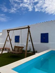 a swing by a swimming pool and a house at A Casa Azul in Vaiamonte