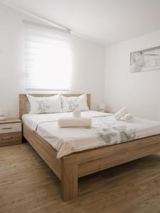 a white bedroom with a large bed with white sheets at Apartments Sofia in Sutomore
