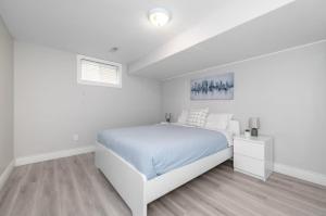a white bedroom with a bed and a window at Bungalow Home in Ottawa