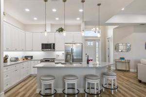 a kitchen with white cabinets and a large island with bar stools at Coastal Paradise Waterfront Pool Home in Bon Terra