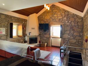 a room with a stone wall with a bed and a fireplace at Casa do Canastro in Vale de Cambra