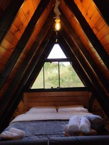 a bed in a wooden attic with a window at Rancho dos lagos in Campo Alegre