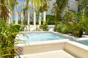 a hot tub in a garden with palm trees at Hotel NYX Cancun in Cancún