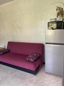 Cette chambre comprend un canapé violet et un réfrigérateur. dans l'établissement Сдается двухкомнатная квартира с балконом в Гонио с прекрасным видом на горы, à Itʼkhvisi