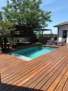 eine Holzterrasse mit einem Pool auf einem Haus in der Unterkunft Villa moderne avec piscine chauffée in Artigues-près-Bordeaux + 14 Fotos