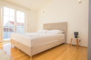 a white bedroom with a bed and a window at House Matilda in Primošten