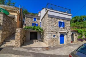 a stone house with blue doors and a balcony at House Maris in Tribalj +70 photos