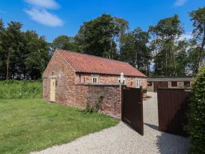 un fienile in mattoni con un cancello in un cortile di Stable Cottage a Stonegrave