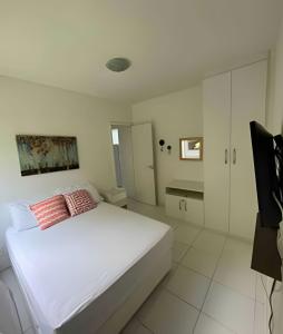 a white bedroom with a large white bed with red pillows at PORTO REAL RESORT - APARTAMENTO VISTA MAR EM CONDOMÍNIO COM PRAIA PRIVATIVA in Mangaratiba