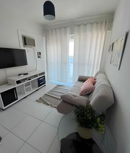 a living room with a couch and a tv at PORTO REAL RESORT - APARTAMENTO VISTA MAR EM CONDOMÍNIO COM PRAIA PRIVATIVA in Mangaratiba