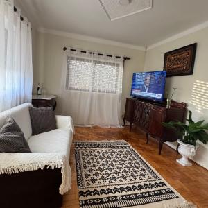 a living room with a white couch and a flat screen tv at Casa de férias in Monte