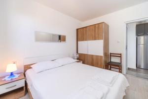 a white bedroom with a bed and a chair at Korak Do Mora in Murvica