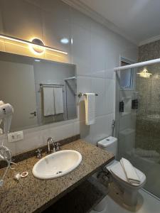 une salle de bain avec un lavabo, des toilettes et une douche dans l'établissement Pousada Sol da Mantiqueira - Inauguração, à Campos do Jordão