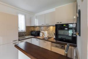una cucina con mobili bianchi e un microonde nero di Bel appartement vue mer ad Agay - Saint Raphael