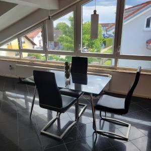 two chairs and a table in a room with windows at Helle gemütliche DG Wohnung, 88qm, klimatisiert in Philippsburg +13 photos