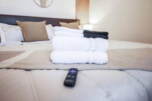 a pile of towels on a bed with a remote control at Stylish & Sunny With Heated Pool In The Foothills! in Phoenix
