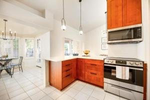 a kitchen with wooden cabinets and a stove at Stylish & Sunny With Heated Pool In The Foothills! in Phoenix