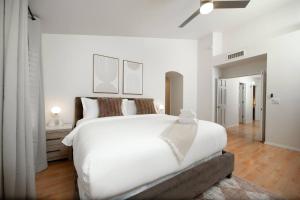 a white bedroom with a large bed with white walls at Stylish & Sunny With Heated Pool In The Foothills! in Phoenix +37 photos