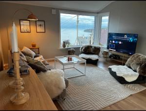 a living room with a large window and a television at Koselig leilighet med utsikt, gåavstand fra sentrum in Stord