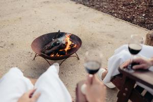 Eine Gruppe von Menschen hält Weingläser neben einem Feuer. in der Unterkunft Wildwood Eco Retreat in Quindalup