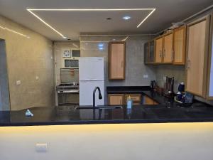 a kitchen with a white refrigerator and wooden cabinets at Pyramids Private Gate in ‘Ezbet `Abd el-Ḥamîd