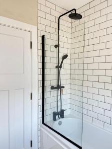 eine Glasdusche im Bad mit Badewanne in der Unterkunft Harbour Mill Cottage in Annalong