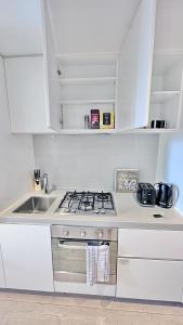 メルボルンにあるHeart CBD White Crystal Residence in Empire Pool n GYMのコンロとシンクのある白いキッチン +6枚の写真