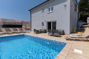a swimming pool with chairs and a house at Villa Marijo with a pool in Novalja