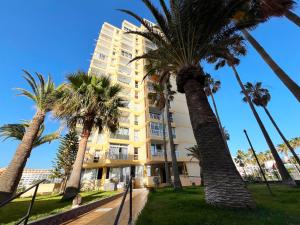 a building with palm trees in front of it at Panoramic & Sea View Holiday Home in Playa de las Américas, Tenerife South in Playa de las Americas