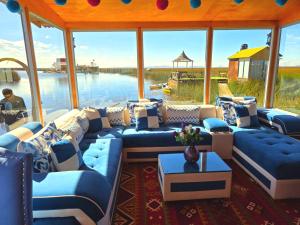 a living room with blue couches and a view of the water at UROS KAY PACHA Lodge in Puno