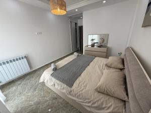 a bedroom with a large bed in a white room at Apartement haut standing in Constantine