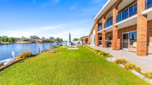 un edificio con césped junto a un cuerpo de agua en Friendship Key, en Forster