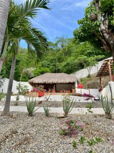 a small hut with a thatched roof in a garden at Casa Blanca in Santa Cruz Huatulco