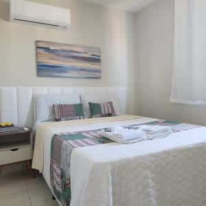 a bedroom with a bed with white sheets and a painting at Callista Residence Flat in Porto De Galinhas